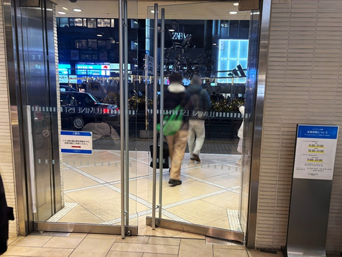 新宿駅東口ルミネエスト1階の出口。扉のすぐ先にタクシー乗り場の看板と車両が見える夜の景色