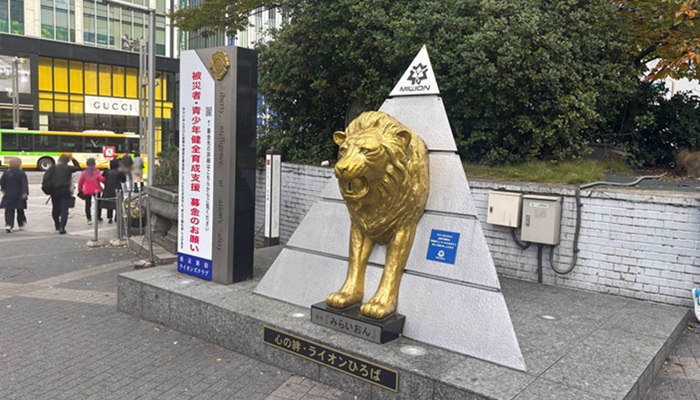 JR新宿駅東口にある黄金のライオン像「みらいおん」。土台に刻まれた名称と、待ち合わせスポットとしての様子。