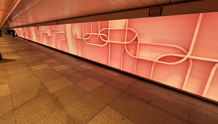 新宿駅東西自由通路の新宿ウォール456。オレンジ色の幾何学模様が映し出された、広々とした通路の景色。