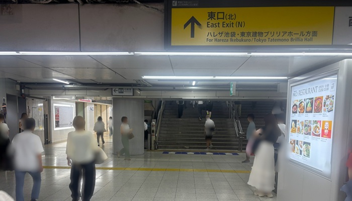 池袋駅東口(北)へ上る階段と頭上の「↑ 東口(北)」案内表示