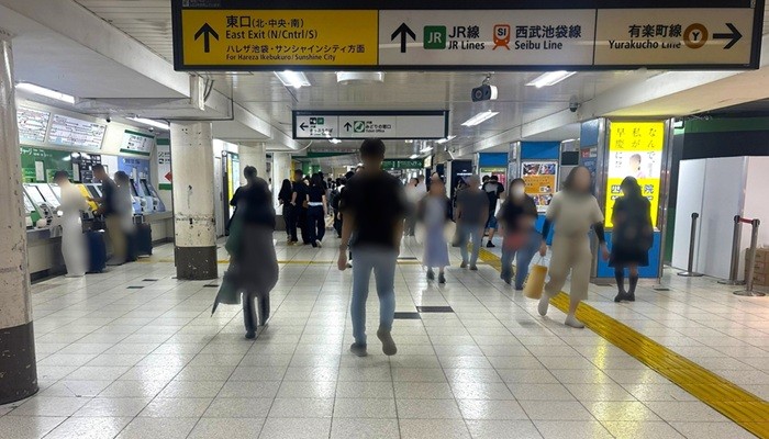 池袋駅地下通路。左手にきっぷ売り場がある。頭上にサンシャインシティ方面や↑東口(北・中央・南)、有楽町線を示す大型案内板