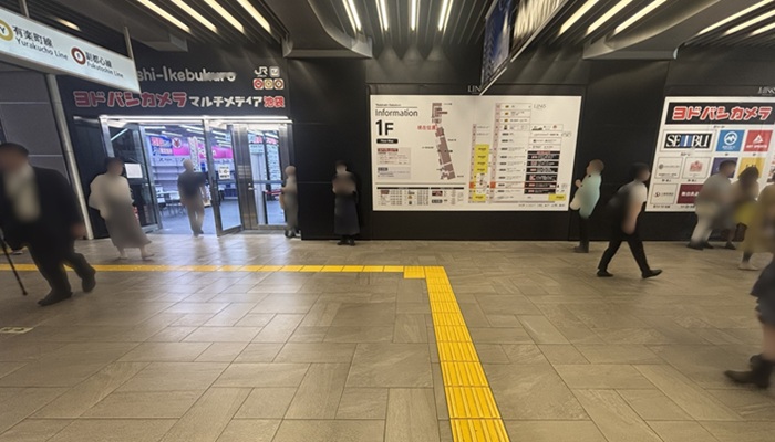 西武池袋線1F改札から35番出口へ向かう通路。正面のヨドバシカメラ入口と案内板の手前を左へ曲がり地下階段へ向かう様子