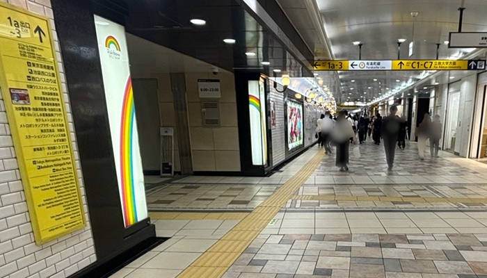 池袋駅の地下通路。左手に「1a-3出口」の黄色い案内板とレインボーの柱